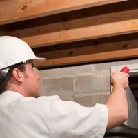 Termite inspection technician checking a basement wall and framing for termite activity in Philadelphia, PA
